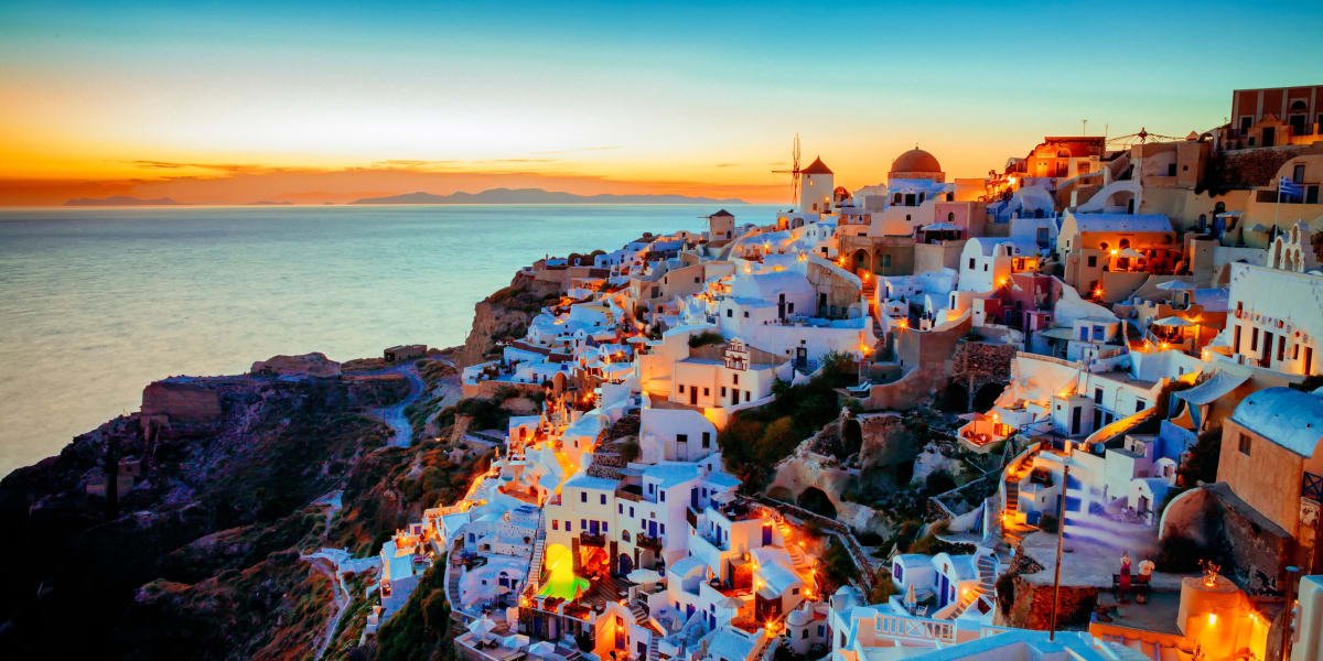 Oia Santorini sunset with white-washed buildings, blue domes, and windmill