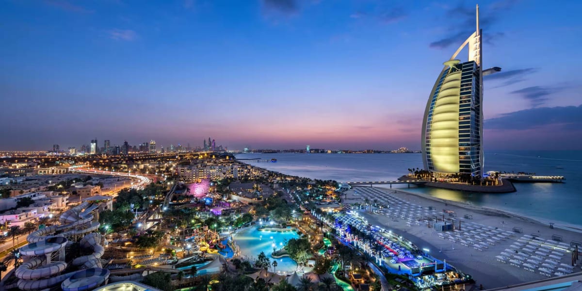 Burj Al Arab hotel at dusk with Dubai skyline and Arabian Gulf